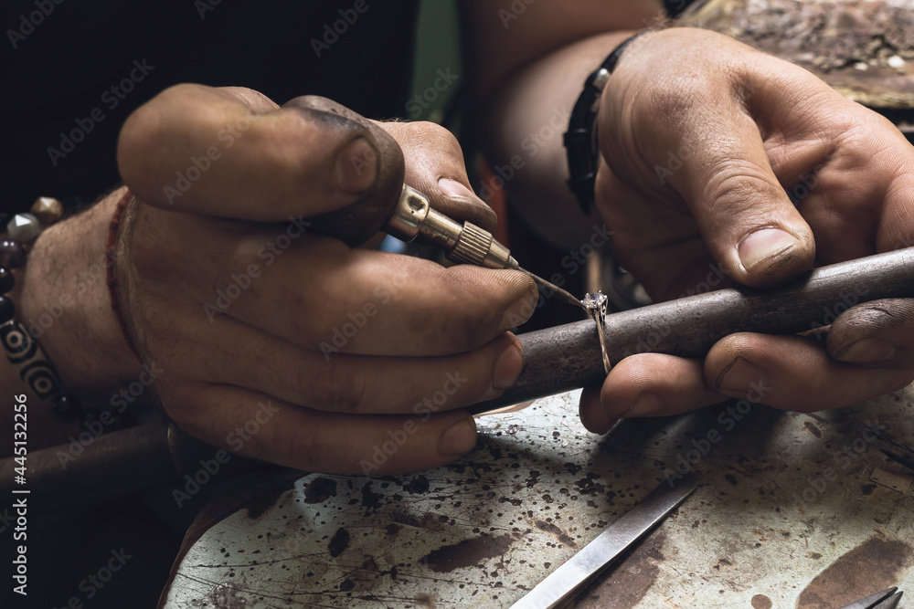 Working process, a jeweler is engaged in the repair of a gold ring with a precious stone in the workshop