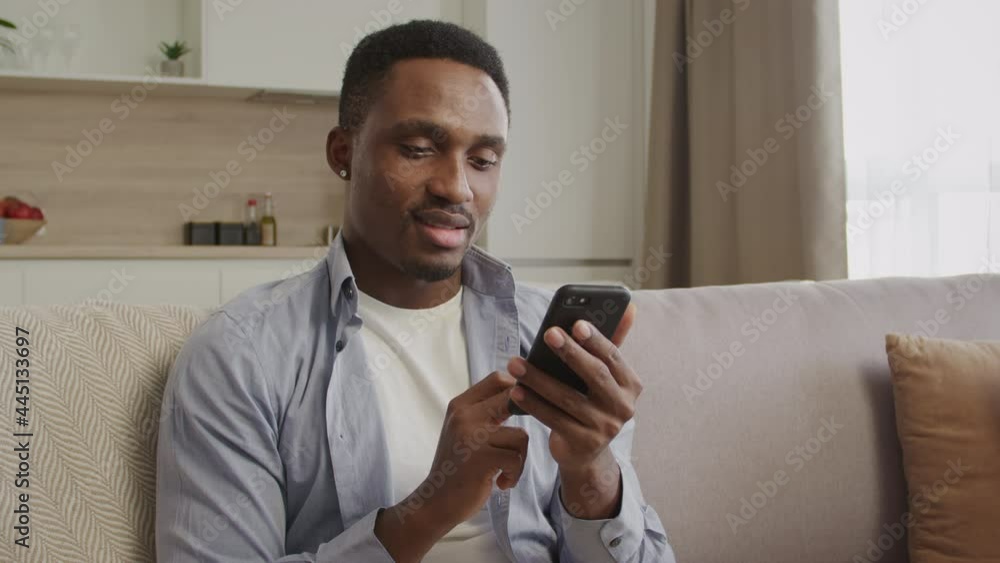 Portrait of a young african american man typing an answer on his smart phone indoors Portrait of a young african american man typing an answer on his smart phone indoors
