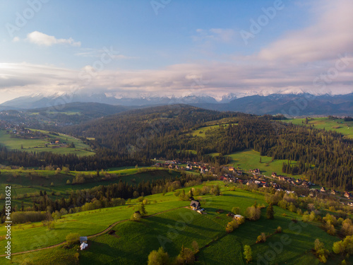 View from above on beautiful green meadows, snow-capped peaks of the Tatra Mountains in the distance. View from the air. View from the drone. © gkrphoto