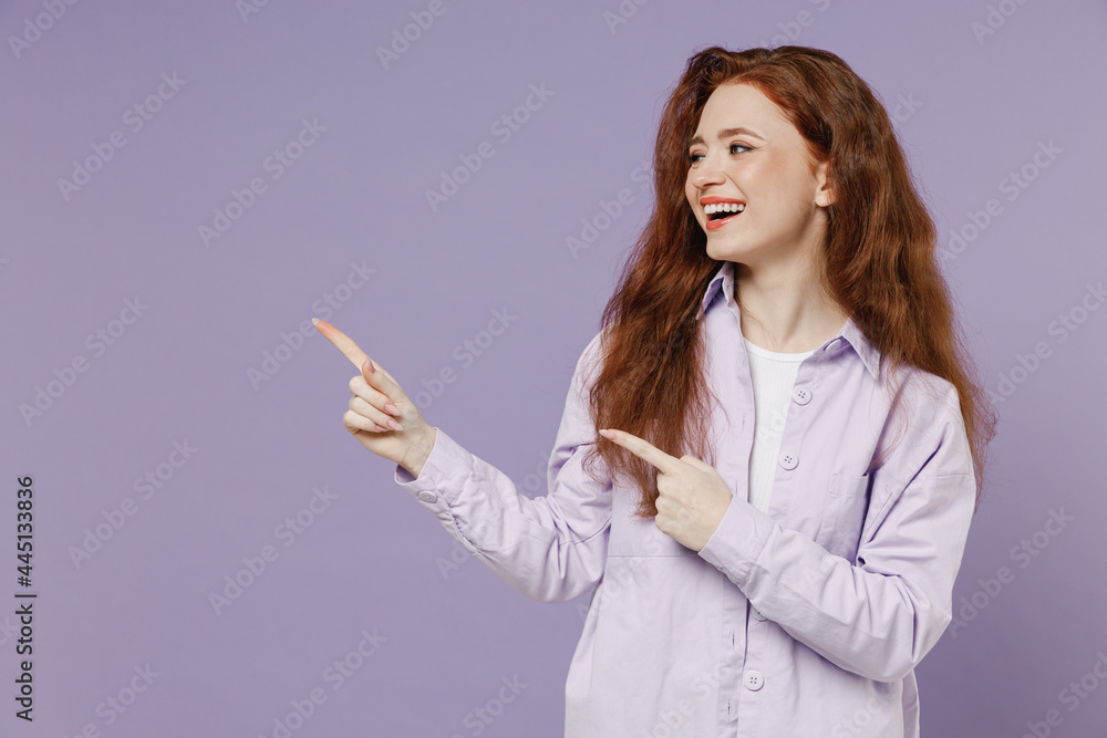 Overjoyed cheerful young redhead curly green-eyed woman 20s wear white T-shirt violet jacket point on workspace area copy space mock up isolated on pastel purple color wall background studio portrait Overjoyed cheerful young redhead curly green-eyed woman 20s wear white T-shirt violet jacket point on workspace area copy space mock up isolated on pastel purple color wall background studio portrait