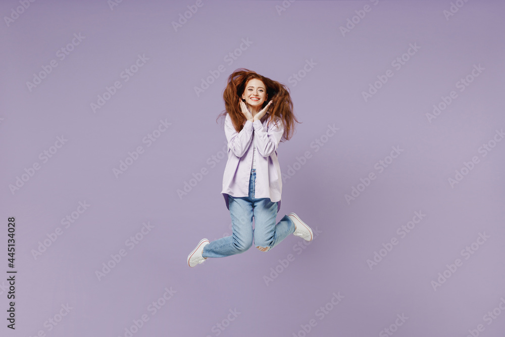 Full size body length happy smiling young redhead curly green-eyed woman 20s wears white T-shirt violet jacket jumping spreading hands isolated on pastel purple color wall background studio portrait.