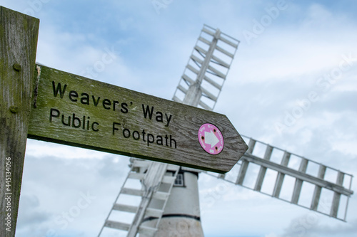 Close up of Weavers Way public footpath sign at Thurne in the Norfolk Broads. Against the backdrop of a blurred/bokeh Thurne Mill.