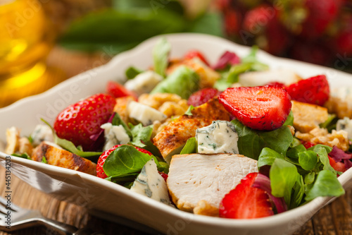 Delicious salad with fried chicken, blue cheese, strawberries and walnuts. Front view.