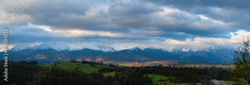 A beautiful panorama of the entire range of the Tatra Mountains. The colorful rays of the sun illuminate the snow-covered  white mountains. The view at sunrise. Poland