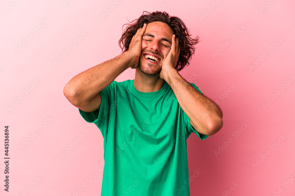 Young caucasian man isolated on pink bakcground laughs joyfully keeping hands on head. Happiness concept. Young caucasian man isolated on pink bakcground laughs joyfully keeping hands on head. Happiness concept.