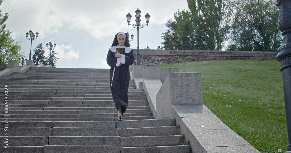 Young nun with Bible walking outdoors Young nun with Bible walking outdoors
