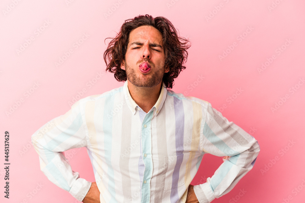 Young caucasian man isolated on pink bakcground funny and friendly sticking out tongue. Young caucasian man isolated on pink bakcground funny and friendly sticking out tongue.
