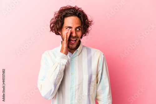 Young caucasian man isolated on pink bakcground shouting excited to front.