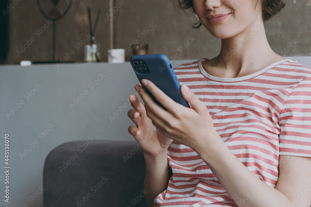 Cropped up photo shot young smiling happy 20s in casual clothes sitting on grey sofa using mobile cell phone chat online look aside rest relax indoors flat at home People lifestyle leisure concept Cropped up photo shot young smiling happy 20s in casual clothes sitting on grey sofa using mobile cell phone chat online look aside rest relax indoors flat at home People lifestyle leisure concept