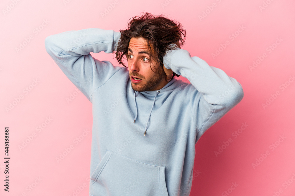 Young caucasian man isolated on pink bakcground screaming, very excited, passionate, satisfied with something.