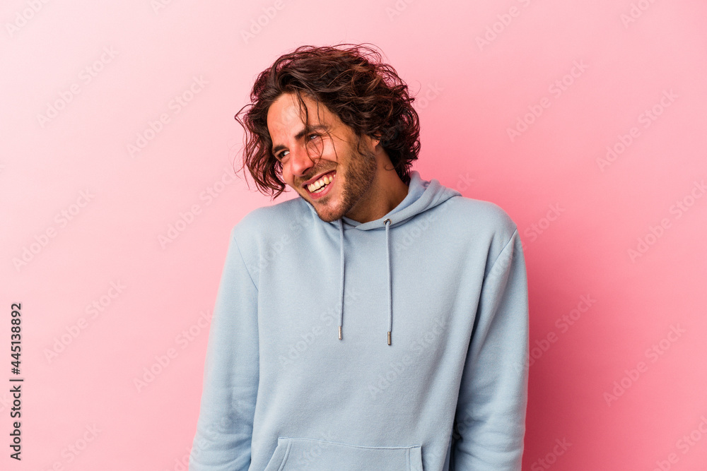 Young caucasian man isolated on pink bakcground laughs and closes eyes, feels relaxed and happy. Young caucasian man isolated on pink bakcground laughs and closes eyes, feels relaxed and happy.