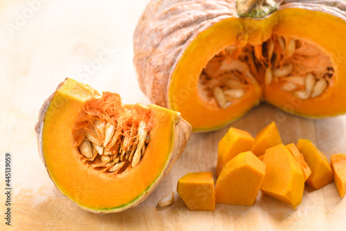 Close up of cutting organic pumpkin on wooden background