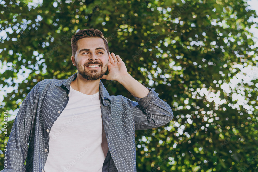 Young smiling satisfied man in blue casual shirt walk listening chirping birds rest relax in spring sunshine forest green city park go down alley outdoors on nature Urban lifestyle leisure concept Young smiling satisfied man in blue casual shirt walk listening chirping birds rest relax in spring sunshine forest green city park go down alley outdoors on nature Urban lifestyle leisure concept