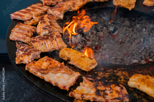 Process of cooking fresh juicy meat steaks on brazier at summer local food market - close up view. Outdoor cooking, gastronomy, cookery, street food concept