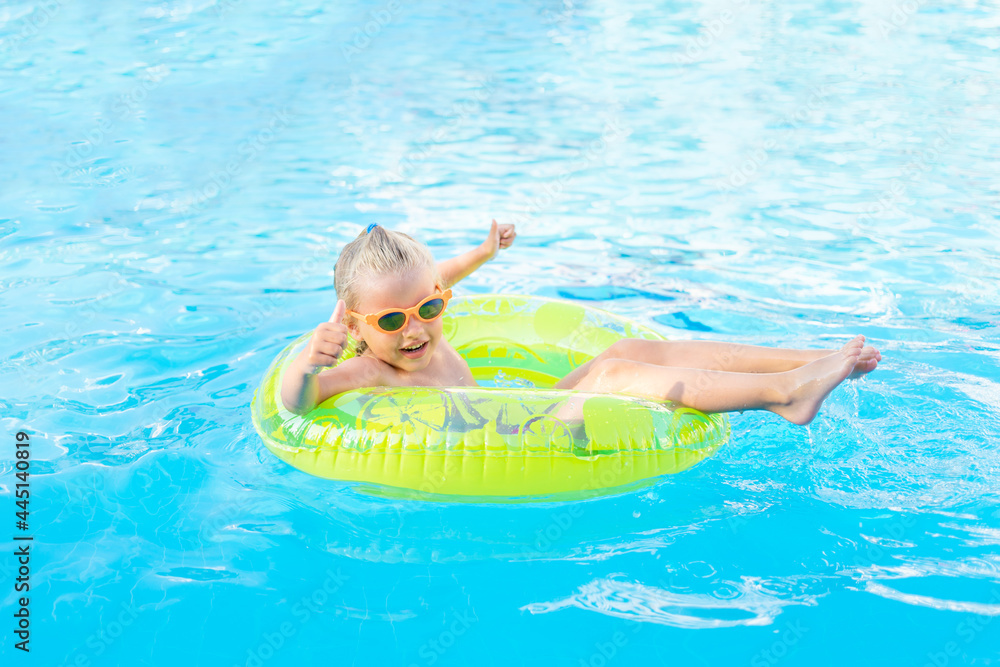 baby girl swims in the pool with an inflatable yellow circle in summer and shows the class, the concept of travel and recreation