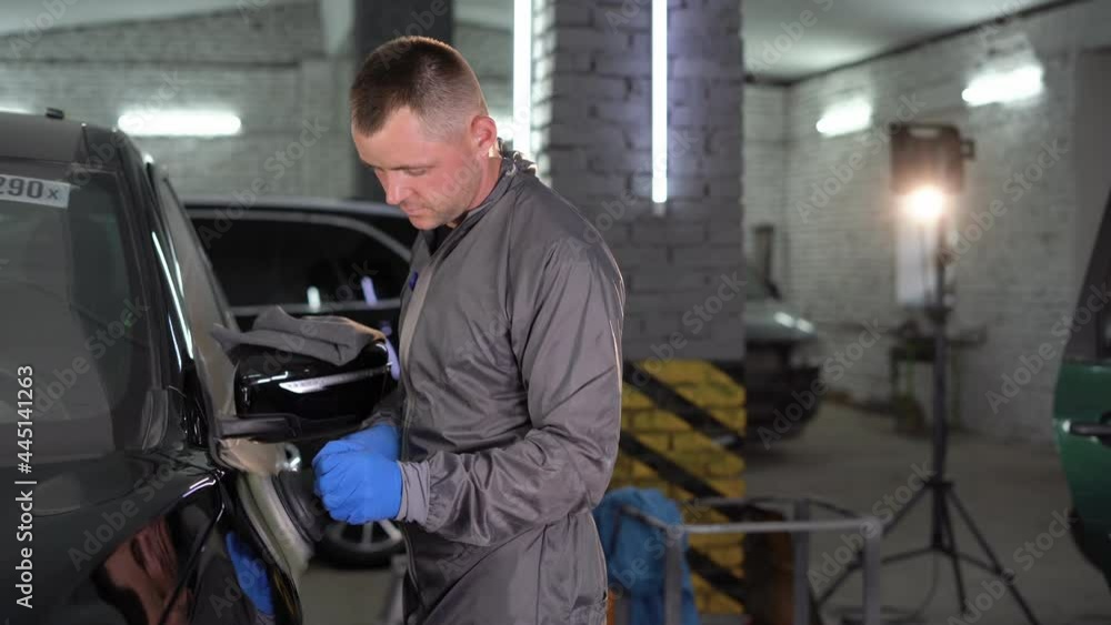 Professional auto retailer holding a rotary polisher while polishing the paint surface of a shiny black car. Car detailing, car wash and color correction concept. Professional auto retailer holding a rotary polisher while polishing the paint surface of a shiny black car. Car detailing, car wash and color correction concept.