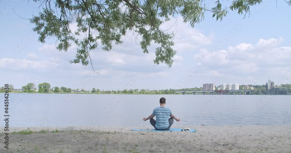 Sporty young man practicing yoga near river Sporty young man practicing yoga near river