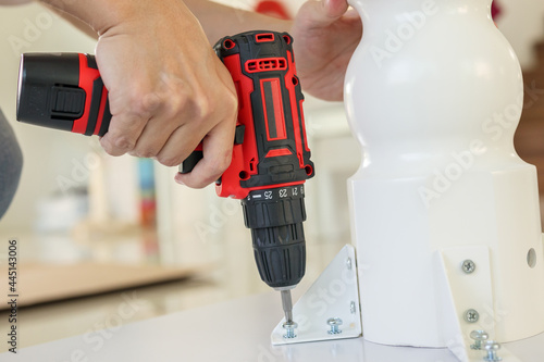 Wallpaper Mural man assembling white table furniture at home using cordless screwdriver Torontodigital.ca