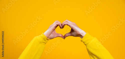 Hands making heart shape isolated on a yellow background - Love and minimal fashion concept	
