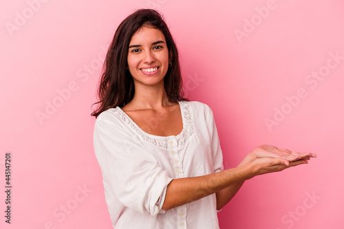 Young caucasian woman isolated on pink background holding a copy space on a palm.