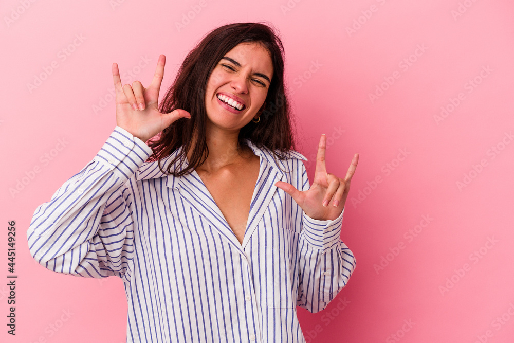 Young caucasian woman isolated on pink background showing a horns gesture as a revolution concept. Young caucasian woman isolated on pink background showing a horns gesture as a revolution concept.