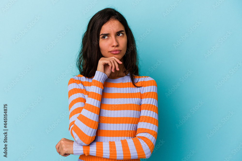 Young caucasian woman isolated on blue background looking sideways with doubtful and skeptical expression. Young caucasian woman isolated on blue background looking sideways with doubtful and skeptical expression.