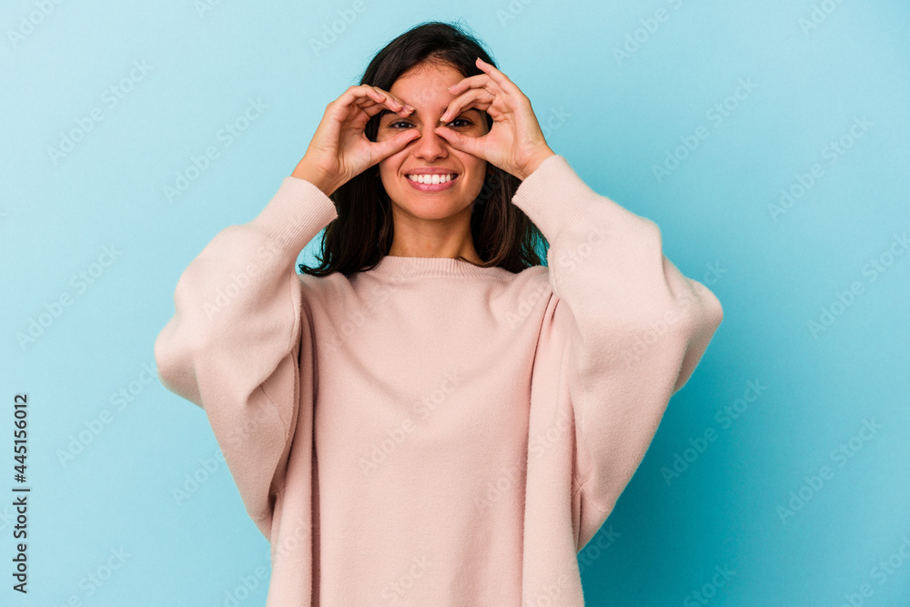 Young caucasian woman isolated on blue background showing okay sign over eyes Young caucasian woman isolated on blue background showing okay sign over eyes