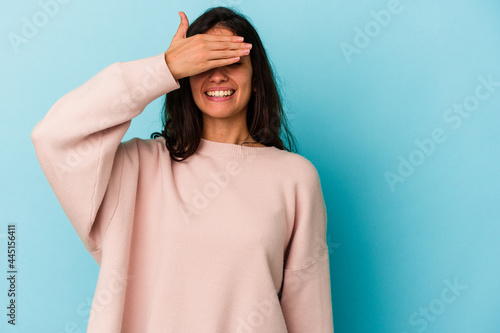 Young caucasian woman isolated on blue background covers eyes with hands, smiles broadly waiting for a surprise.