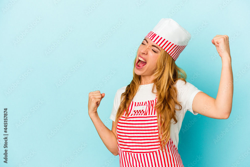 Caucasian ice cream maker woman isolated on blue background raising fist after a victory, winner concept. Caucasian ice cream maker woman isolated on blue background raising fist after a victory, winner concept.
