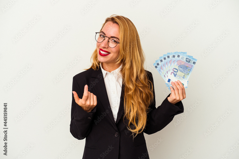 Caucasian business woman holding bills isolated on white background pointing with finger at you as if inviting come closer. Caucasian business woman holding bills isolated on white background pointing with finger at you as if inviting come closer.
