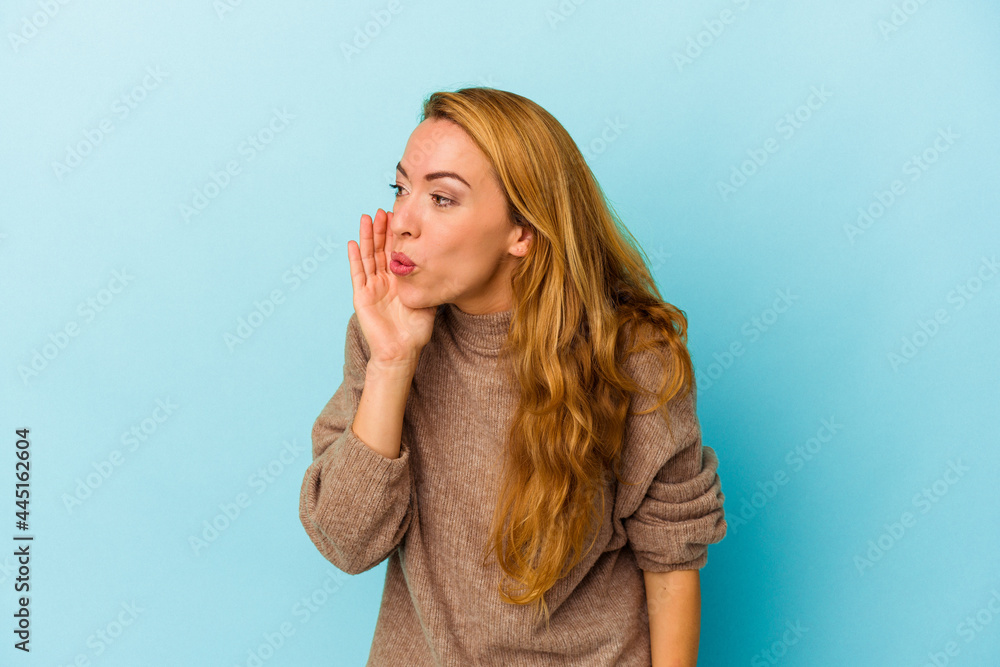 Caucasian woman isolated on blue background is saying a secret hot braking news and looking aside Caucasian woman isolated on blue background is saying a secret hot braking news and looking aside