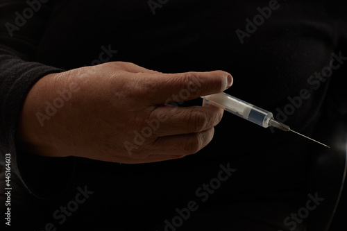 Woman hand with a syringe isolated on black background