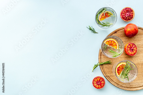 Red orange lemonade in glasses with ice and rosemary