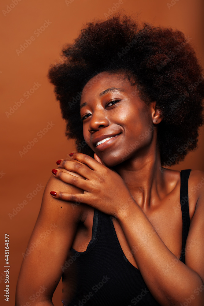 pretty young african american woman with curly hair posing cheerful gesturing on brown background, lifestyle people concept pretty young african american woman with curly hair posing cheerful gesturing on brown background, lifestyle people concept