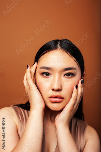 young pretty asian woman cheerful smiling posing on warm brown background, lifestyle people concept