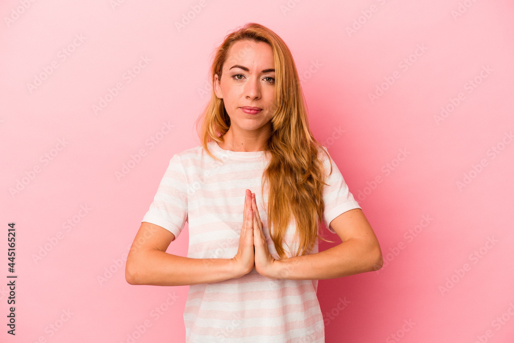 Caucasian blonde woman isolated on pink background praying, showing devotion, religious person looking for divine inspiration. Caucasian blonde woman isolated on pink background praying, showing devotion, religious person looking for divine inspiration.