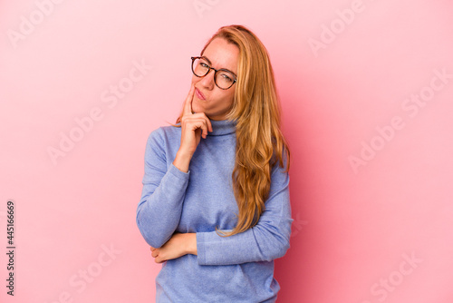 Caucasian blonde woman isolated on pink background contemplating  planning a strategy  thinking about the way of a business.