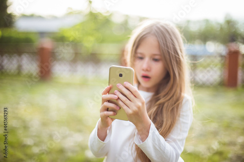 beautiful  girl in a white blouse with smartphone in nature in sunlight