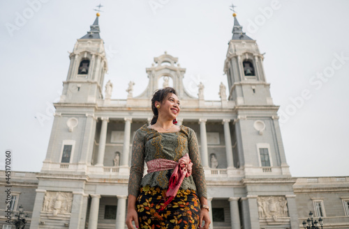 young happy Indonesian woman from Bali having vacation in Europe - attractive and cheerful Balinese tourist girl in traditional outfit touring in the city enjoying holidays trip