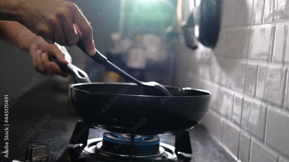 Asian man cooking fried chicken in kitchen of home He holds spatula and pan. with gas stove that is frying to thai food video slowmotion Asian man cooking fried chicken in kitchen of home He holds spatula and pan. with gas stove that is frying to thai food video slowmotion