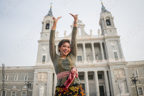 young happy Indonesian woman from Bali having vacation in Europe - attractive and cheerful Balinese tourist girl in traditional outfit touring in the city enjoying holidays trip © TheVisualsYouNeed