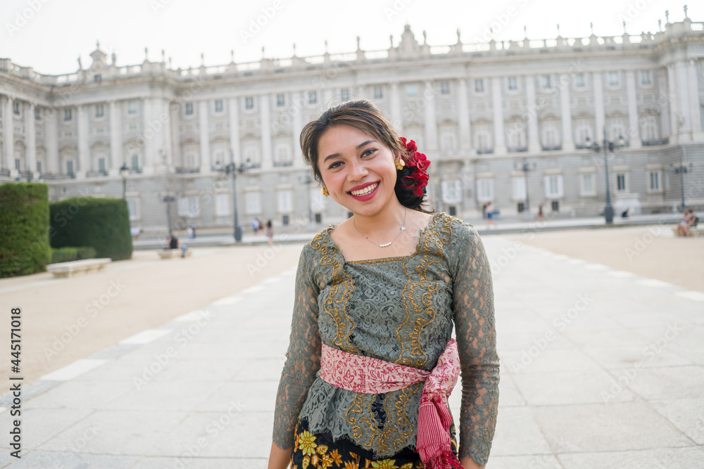young happy Indonesian woman from Bali having vacation in Europe - beautiful and cheerful Balinese tourist girl in traditional outfit touring in the city enjoying holidays