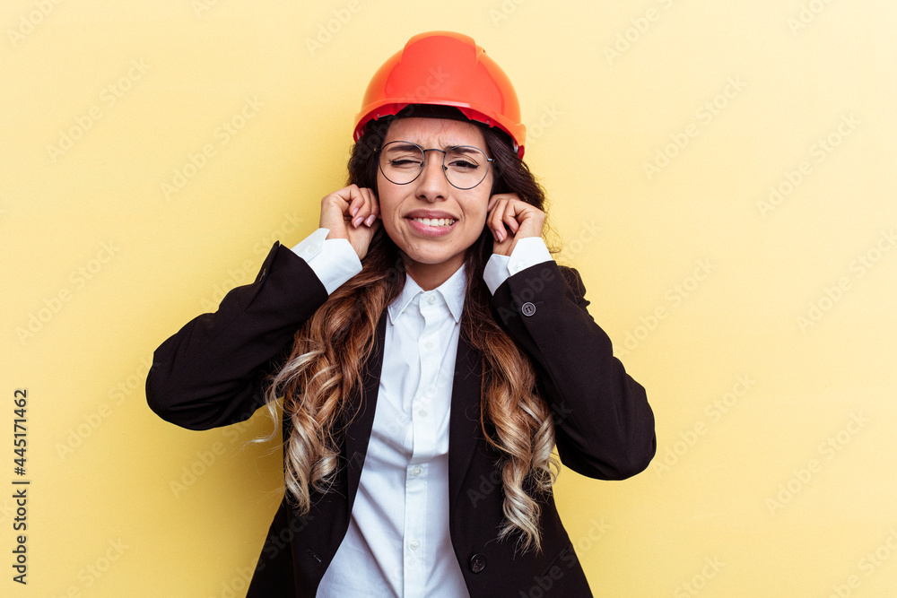 Young architect mixed race woman isolated on yellow background covering ears with hands.