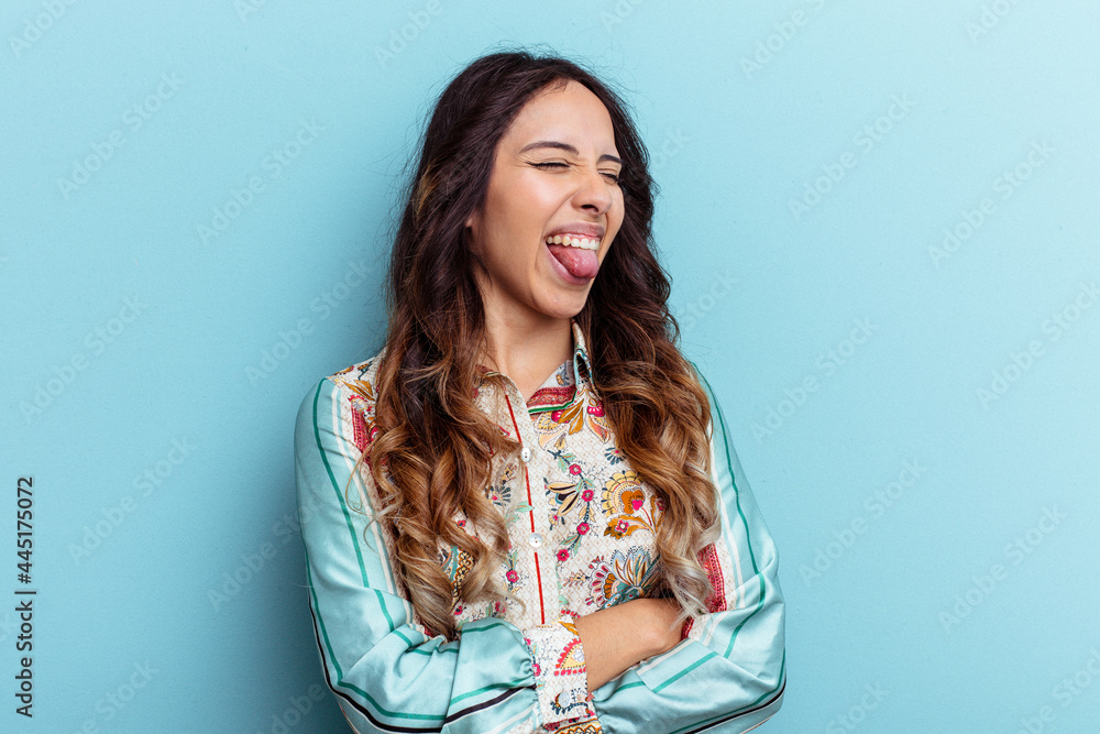 Young mexican woman isolated on blue background funny and friendly sticking out tongue. Young mexican woman isolated on blue background funny and friendly sticking out tongue.