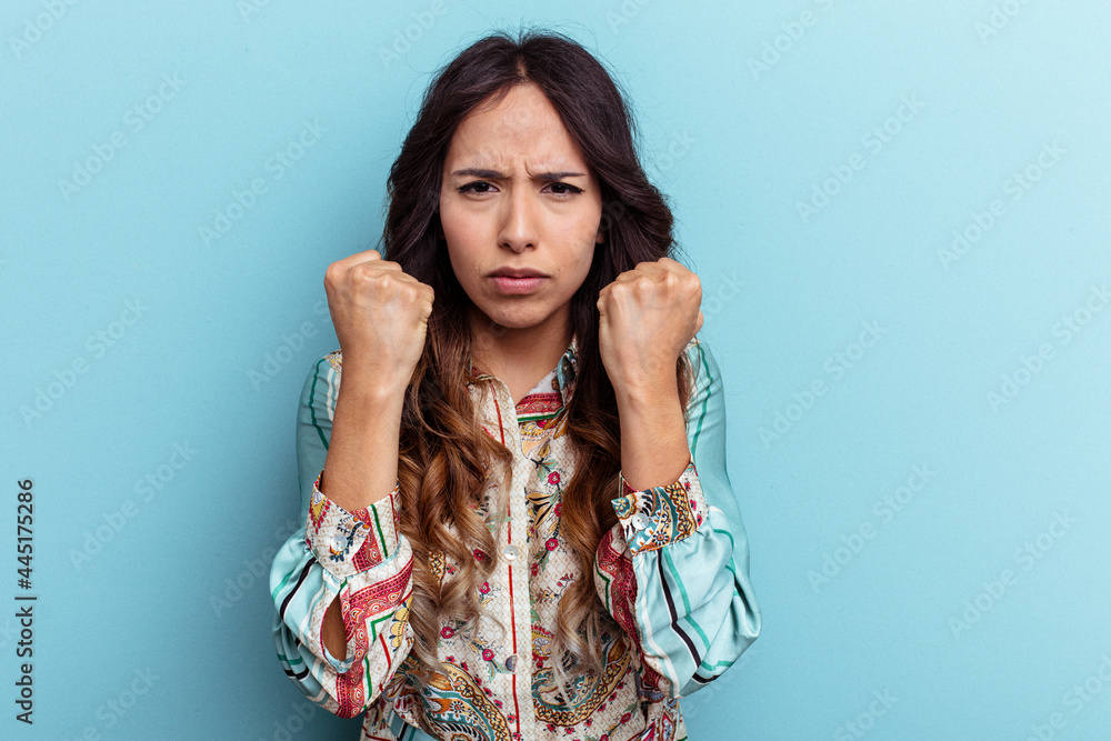 Young mexican woman isolated on blue background showing fist to camera, aggressive facial expression. Young mexican woman isolated on blue background showing fist to camera, aggressive facial expression.