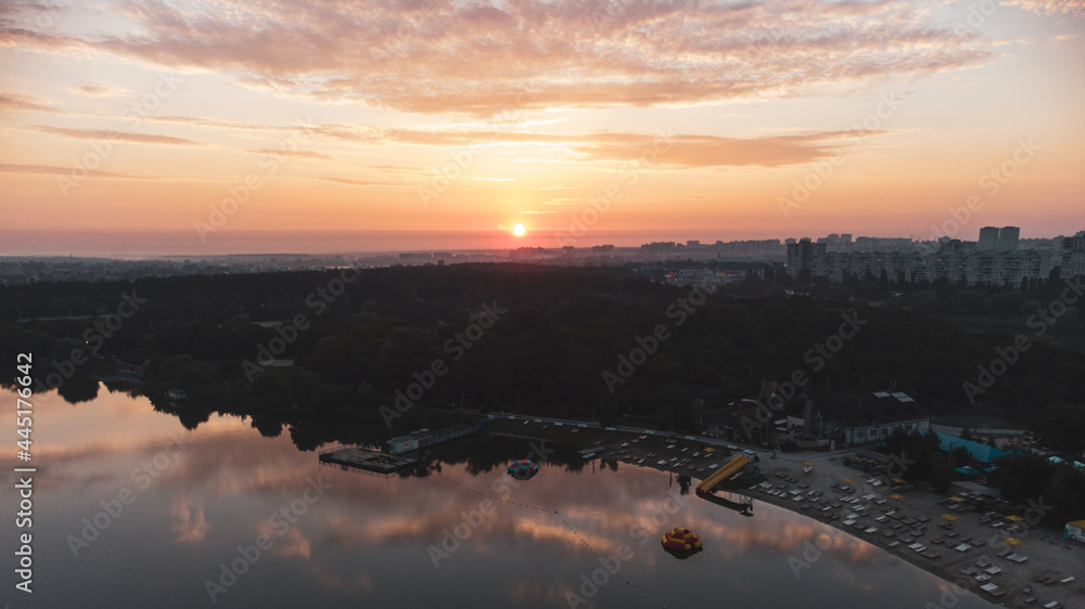Scenic aerial sunrise above beach with clouds reflecting in mirror water surface on wide river. Early morning, dawn in Kharkiv Zhuravlivskyy Hidropark from sky. Drone photography