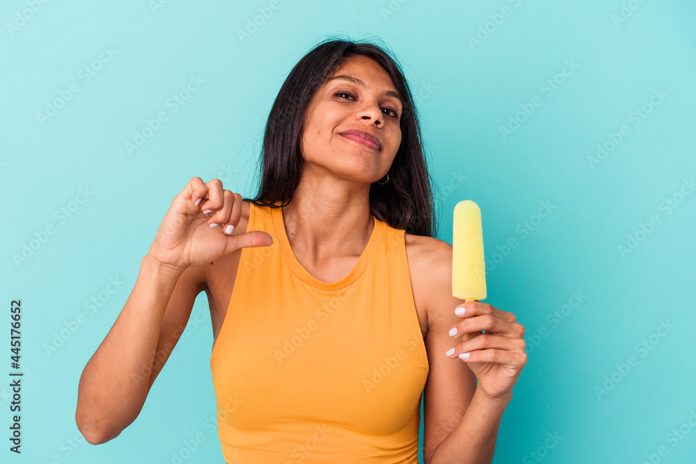 Young latin woman holding ice cream isolated on blue background feels proud and self confident, example to follow. Young latin woman holding ice cream isolated on blue background feels proud and self confident, example to follow.