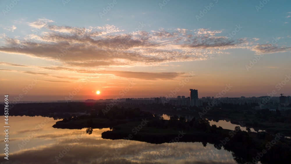 Aerial sunrise with clouds reflecting in water surface on wide river. Early morning, dawn in Kharkiv Zhuravlivskyy Hidropark from sky. Drone photography
