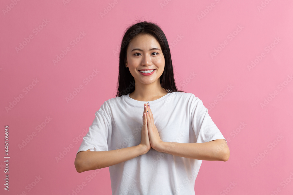 Namaste Portrait of asian woman holding palms together and bowing in asian greeting gesture against pink background Namaste Portrait of asian woman holding palms together and bowing in asian greeting gesture against pink background