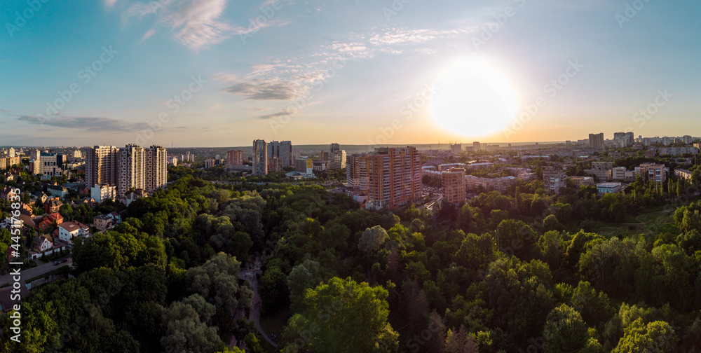 Aerial sunset panorama view on green summer Kharkiv city center popular recreation park Sarzhyn Yar. Botanical garden with water spring and playground in residential area in sunlight
